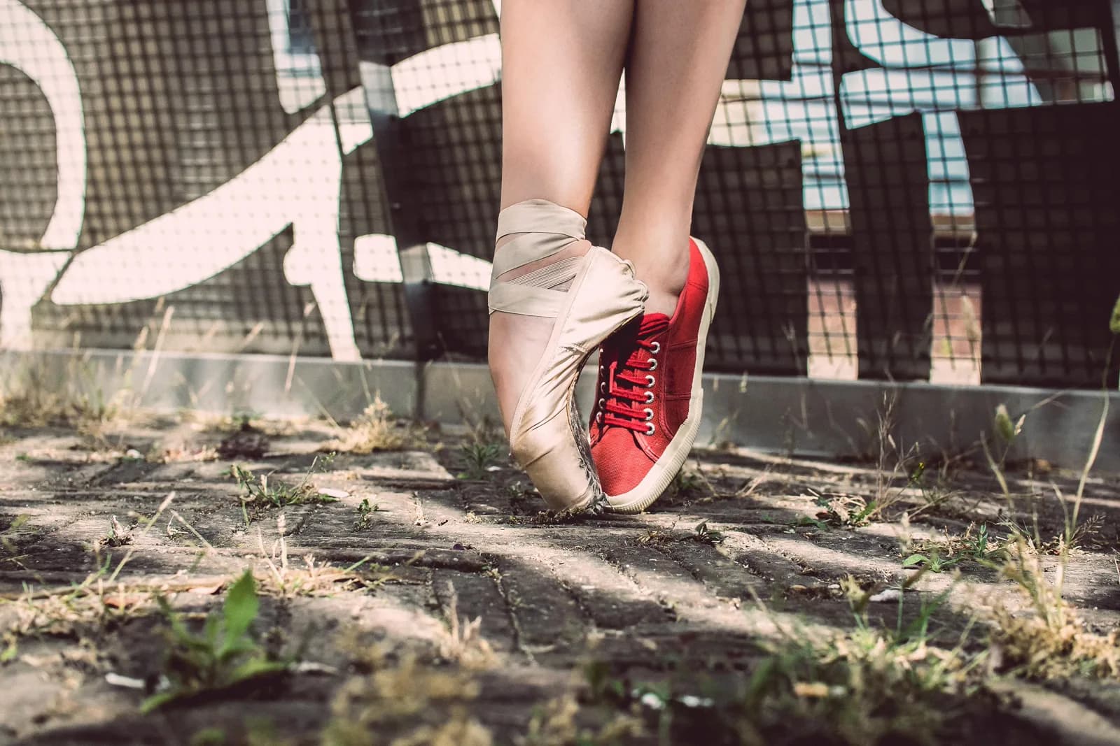 A woman wearing a ballet slipper on one foot and a tennis shoe on the other.